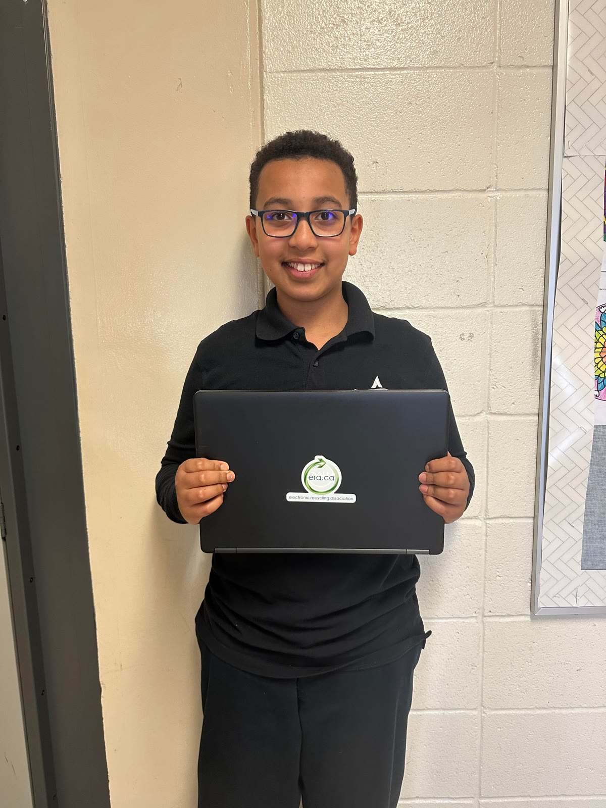 A student holding a refurbished laptop donated through the ERA network