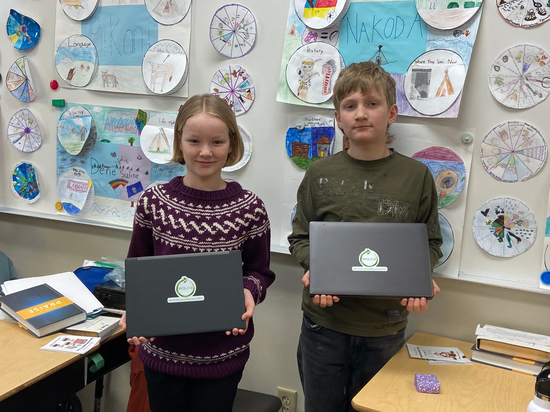 Two students holding refurbished ERA laptops in their classroom