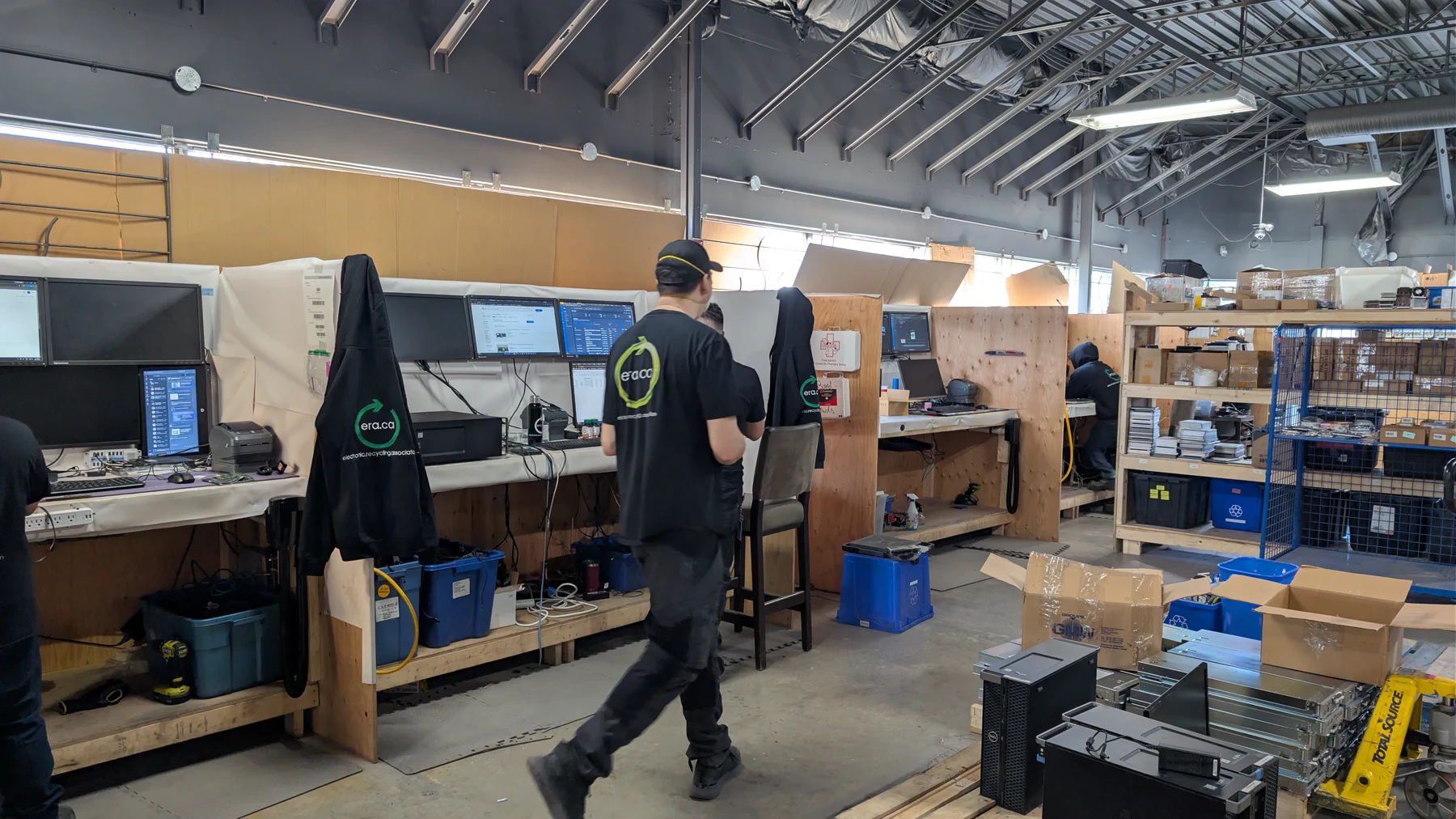 ERA technicians processing and recording technology at a warehouse workstation